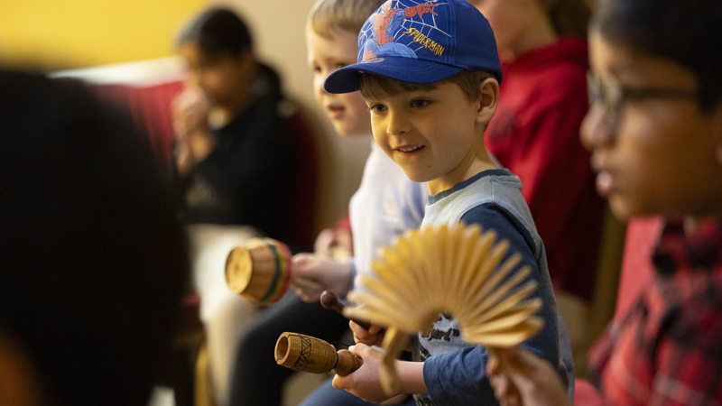 A young boy sitting amongst a group playing percussion instruments