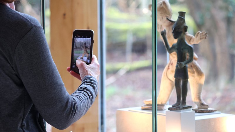 Photograph shows a person using a mobile phone to photograph an object.