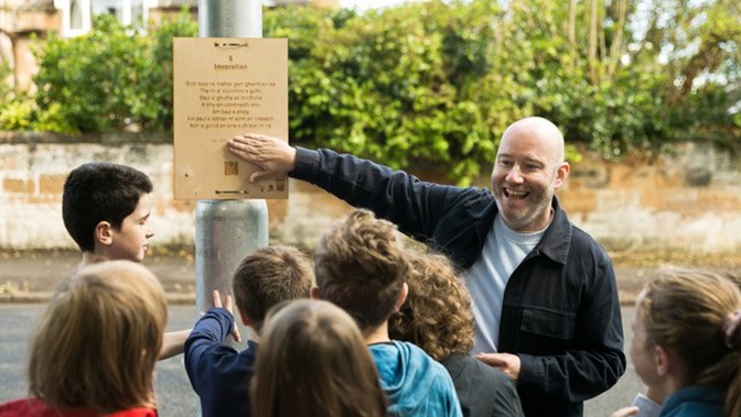 Artist Martin O'Connor shows a qr code to a group of children explaining the new trail.