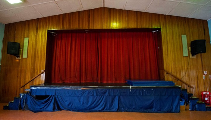 a stage with red curtains closed across it. there are stairs which lead up onto the stage from both sides