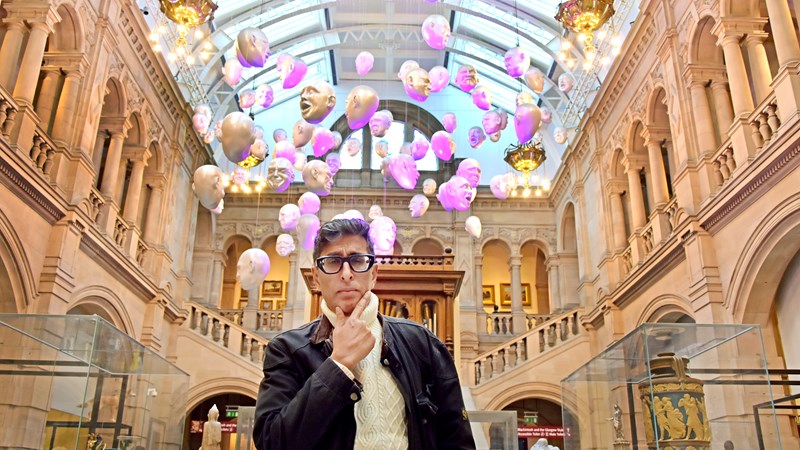 Photograph shows the actor, writer and presenter Sanjeev Kohli standing inside Kelvingrove Art Gallery and Museum