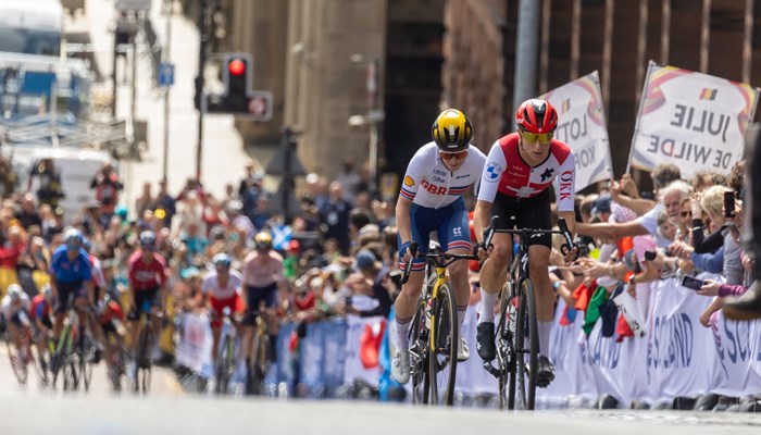 Professional cyclists racing up Montrose Street in Glasgow in front of a cheering crowd during the 2023 UCI Cycling World Championships.