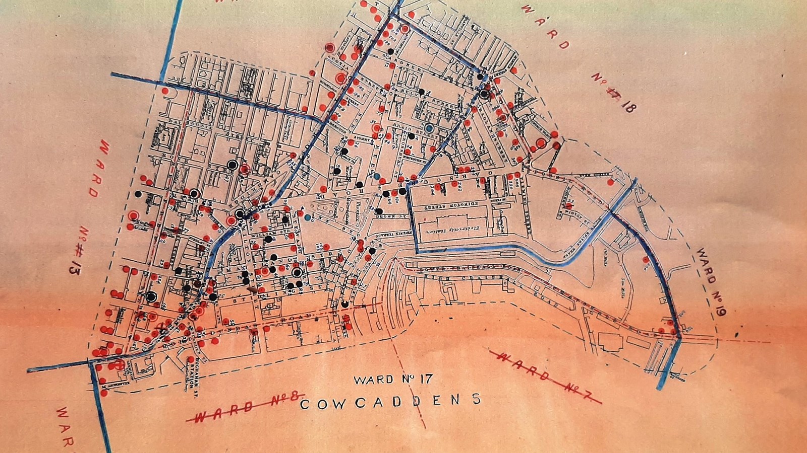 A map of pubs in Glasgow printed on an orange piece of paper and pub markers in red, black and blue.