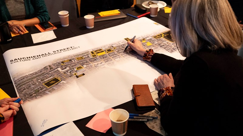 A person writing their ideas during a workshop for the Sauchiehall Street: Culture and Heritage District project.