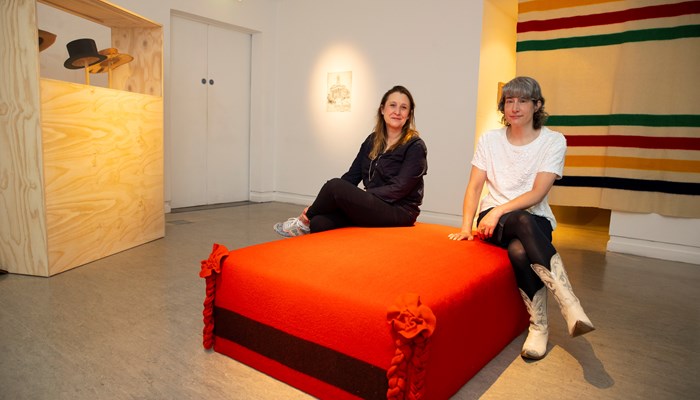 Gallery of Modern Art Curator and Producer Katie Bruce and artist Clara Ursitti sit on a red chair inside the museum's newest exhibition, 'Amik'