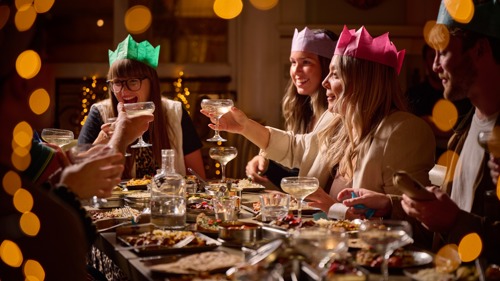 Group of friends wearing Christmas party hats at the dinner table