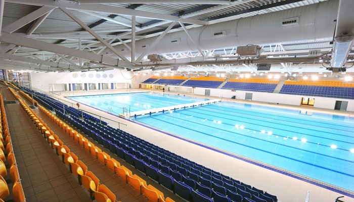 Competition pool within Tollcross International Swimming Centre. There are rows of seats surrounding the pool
