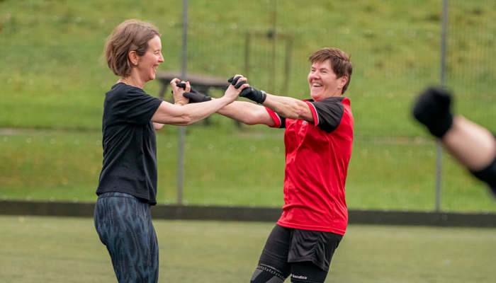 Two smiling football players hold hands, arms raised above their heads, in celebration.