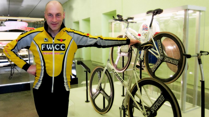 Photograph showing cyclist Graeme Obree standing beside a bike he designed and built himself in the 1990s, smashing the record.