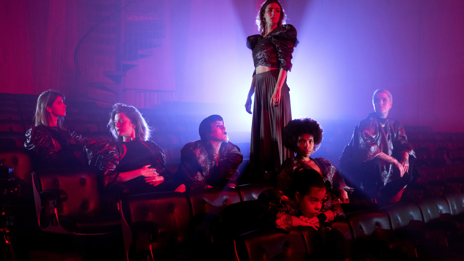 Musicians sit and stand in front of a light inside a church