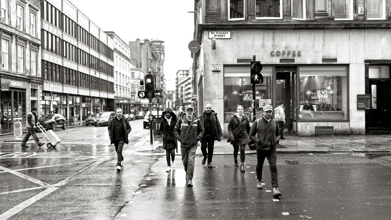 Photograph showing some of the Curious City production team walking across a street in Glasgow. The team are David Scott, Michael MacKinnon, Laura Walker, Bryony Bates, Tracey MacDonald, James Gibson, Anthony Johnston, Caroline Currie, Debora Neto and Alan Braidwood.