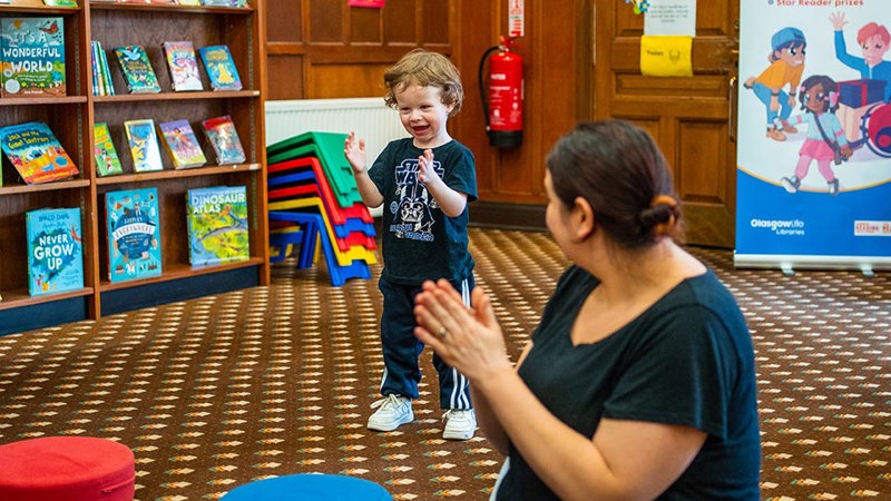 Lady and child in the library clapping hands 