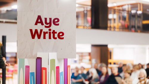 A sign for 'Aye Write' is visible next to an audience at a book festival event