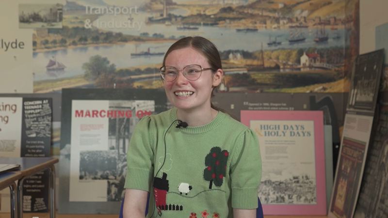 A young person who is a member of the People's Palace Youth Panel smiling while doing an interview.