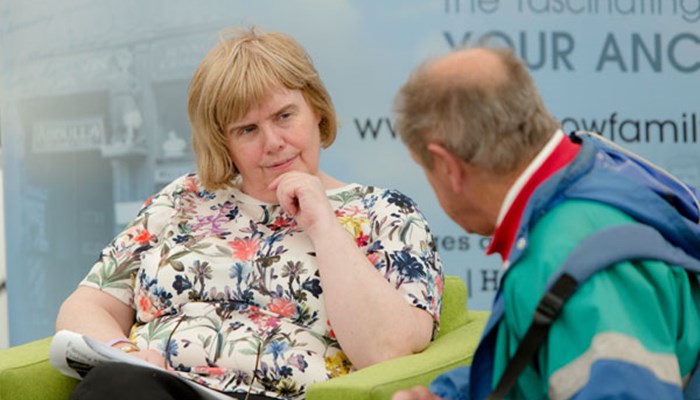 A close up headshot photo of a Family History archivist talking to an attendee of a panel discussion