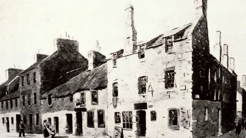 black and white image of old house with small windows and exposed brick