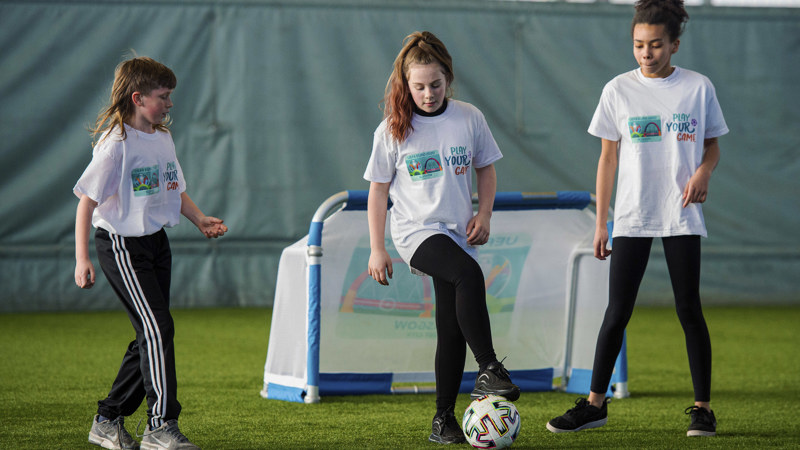 Three young people playing football together