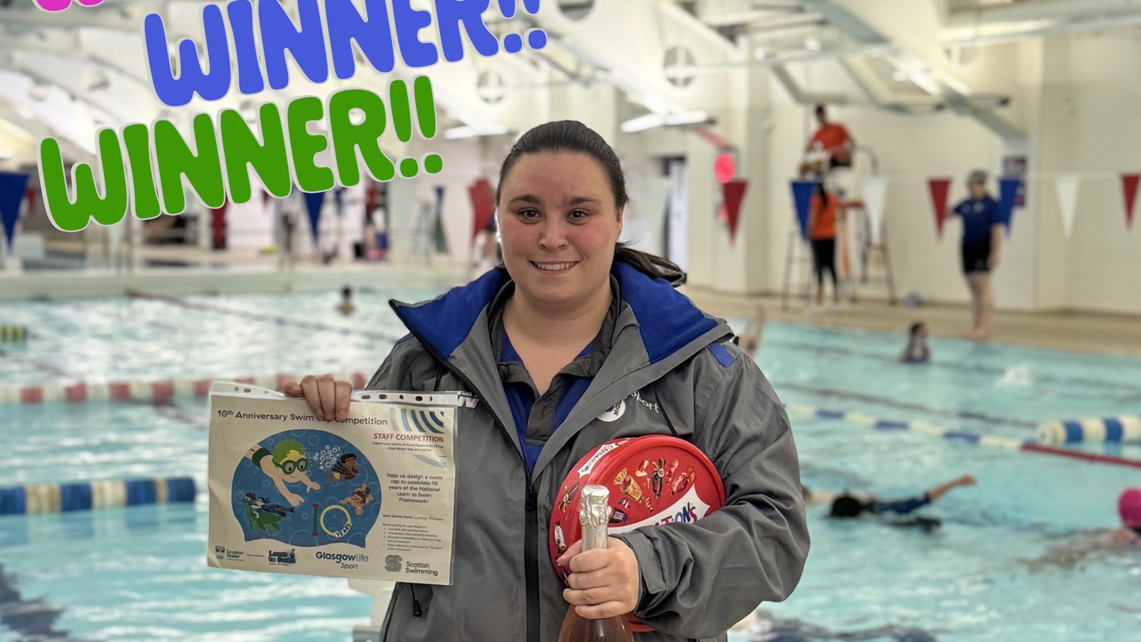 A picture of a woman in front of a swimming pool holding an image of a swimming cap they designed.