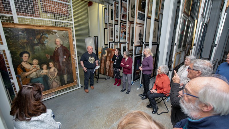 Photograph shows a group tour in progress at Glasgow Museums Resource Centre in the painting store