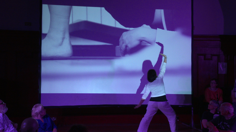 Person performs in front of a project film with purple hues.
