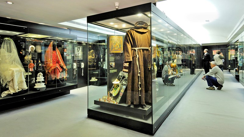 Photograph showing glass cabinets housing displays of Religious clothing.
