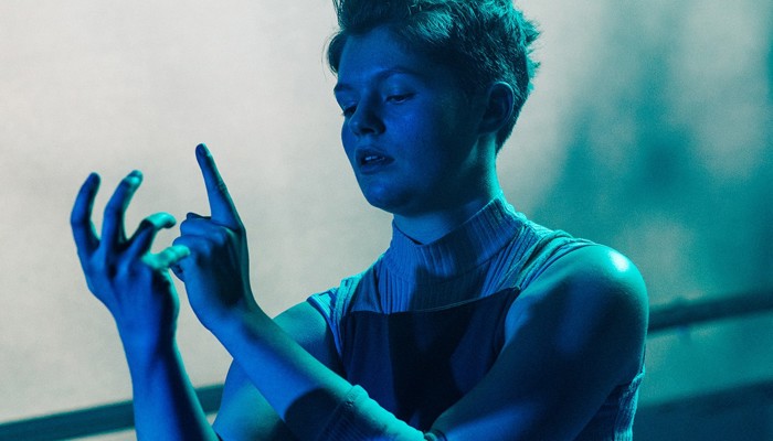 Performer Evie Waddell pictured on stage, lit in blue