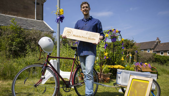 A person stands next to a bike smiling. 