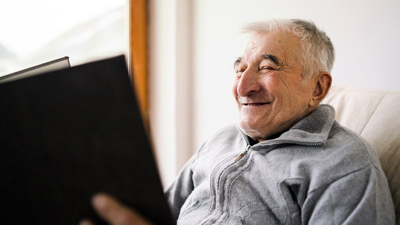 older man looking at a book and smiling