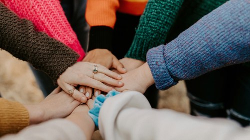 Close up of a group of people holding hands in a circle
