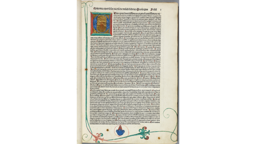 Printed page of an early printed Latin book featuring a large illuminated initial "C" with gold leaf, two columns of dense Blackletter text with red paragraph marks, and decorative floral vines in the margins.