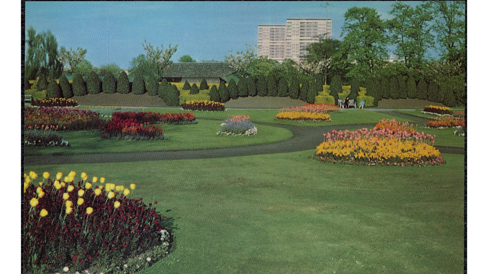 Colour postcard of colourful flower beds and lush green lawns at Victoria Park, with high-rise buildings visible in the background.