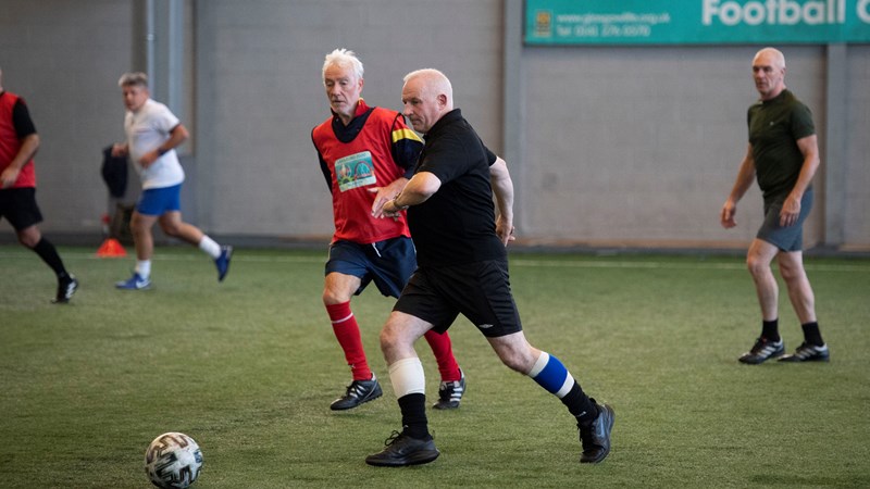 Group of men on an indoor football pitch playing walking football