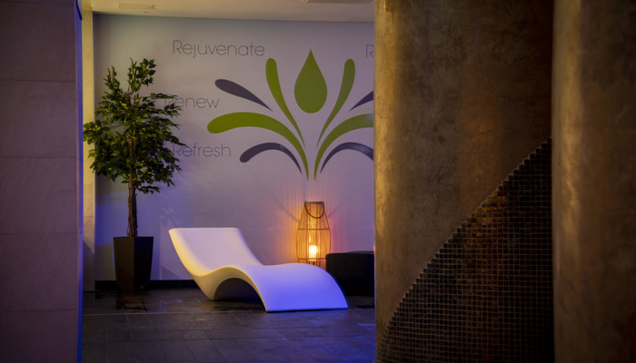 The interior of Refresh Spa in Glasgow, with dim lighting, recliner seat and plant. 