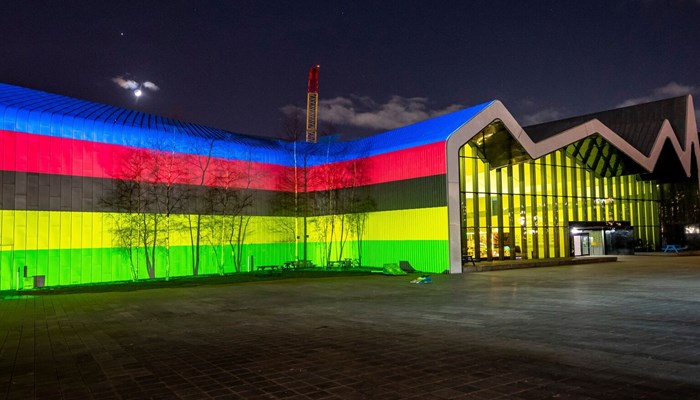 The exterior of the Riverside Museum in Glasgow lit up with multi-coloured lights
