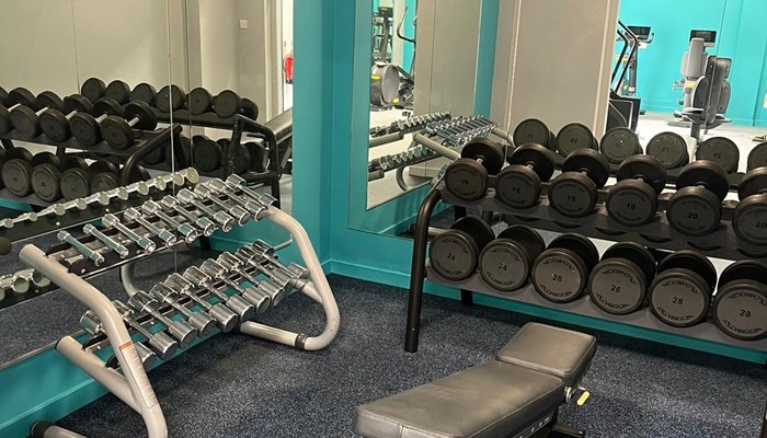 Weights area with mirrored walls, a bench and dumb bells