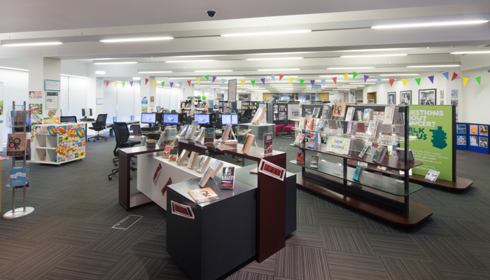 The main area of the library which is modern in style and has bookshelves, PC's and colourful bunting on the ceiling.