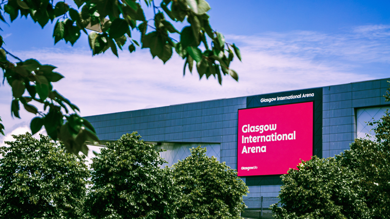 Glasgow International Arena exterior with signage and advertising screen on a sunny day.