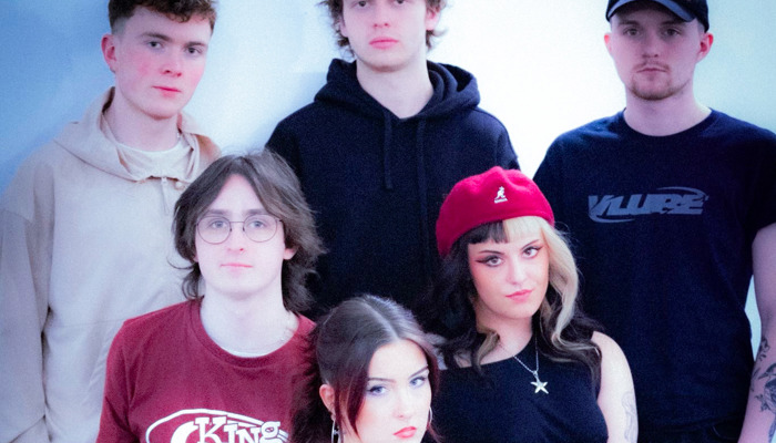 An image of 6 people stood in a triangle looking at the camera