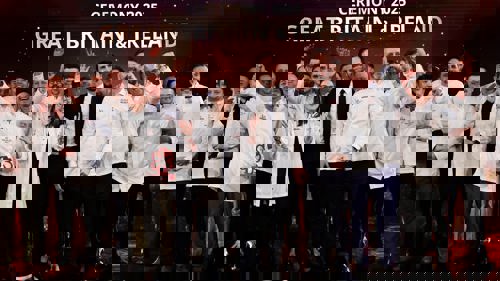 A large group of people wearing white chef jackets on a stage during an awards ceremony