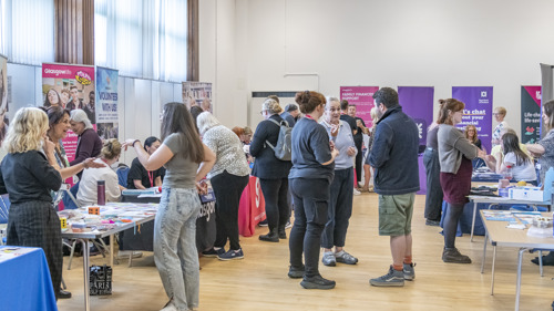 A group of people visiting information stalls in a community centre